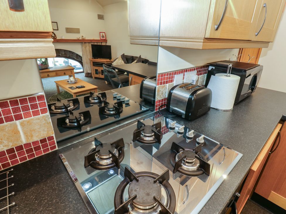 A kitchen with a stove, toaster, and microwave at Green Route Apartment