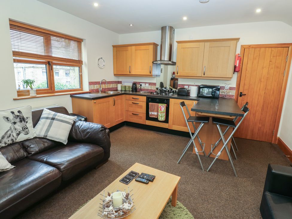 A kitchen with wooden cabinets and a coffee table at Green Route Apartment