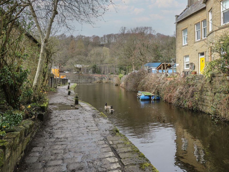 An outdoor scene with a path beside water and buildings at Green Route Apartment in Todmorden