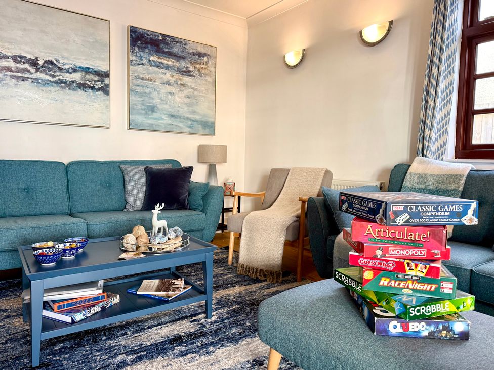 A living room with a sofa and games on a coffee table at Crows Nest Dawlish
