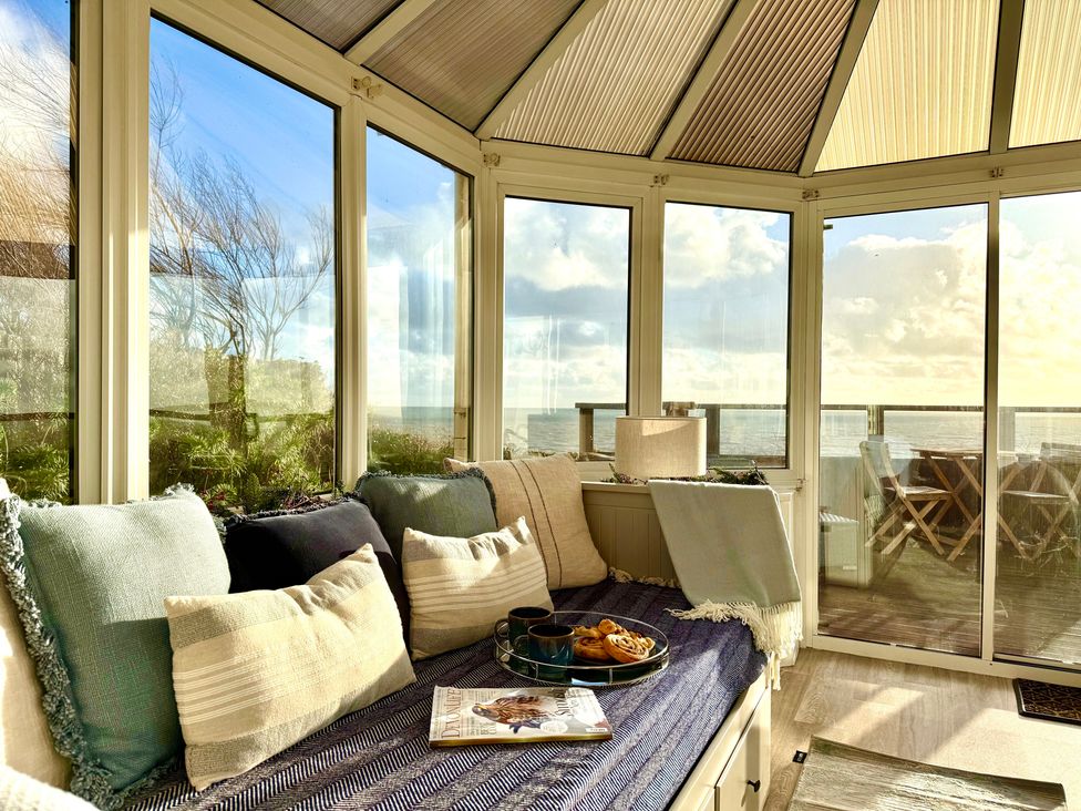 A conservatory with a sofa and table at Crows Nest Dawlish