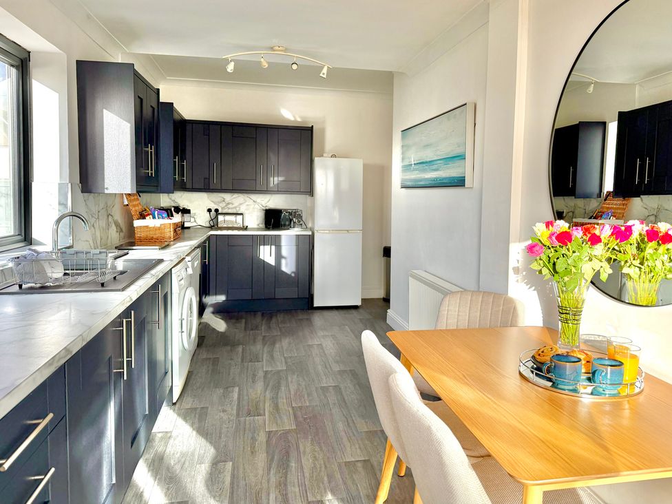 A kitchen with appliances and dining area at Crows Nest Dawlish