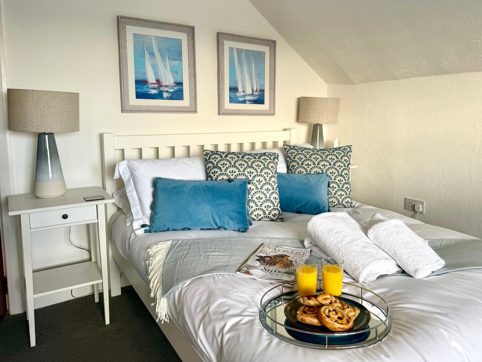 A bedroom with a bed and side table at Crows Nest Dawlish