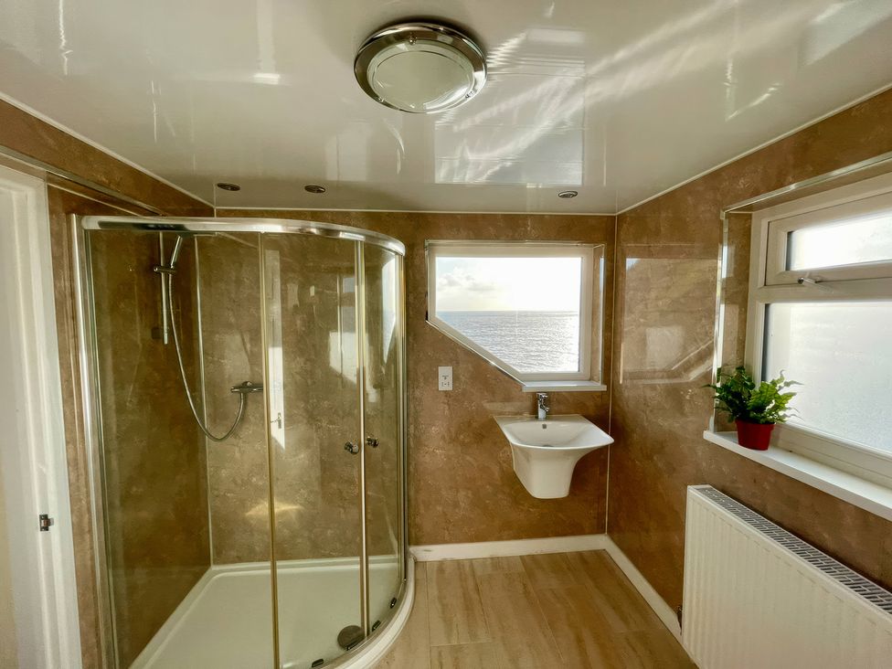 A bathroom with a shower and a wash basin at Crows Nest Dawlish