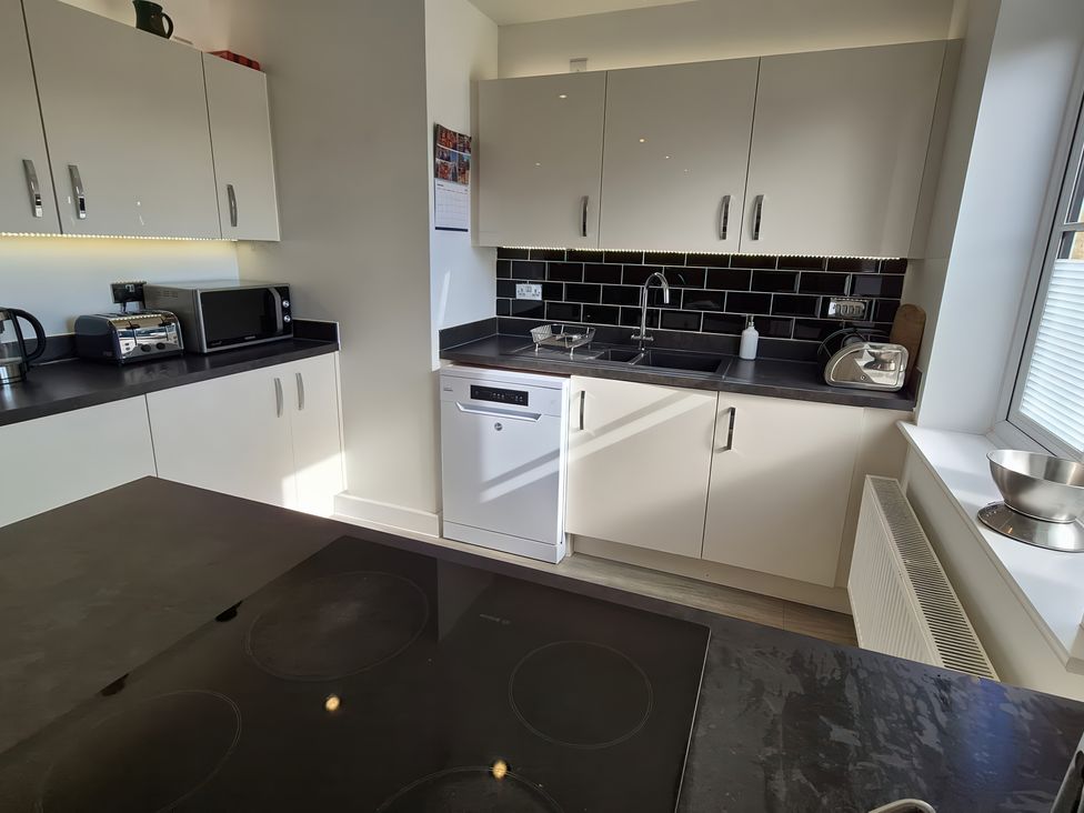 A kitchen with appliances including a kettle, microwave, and dishwasher at 54 swallow road