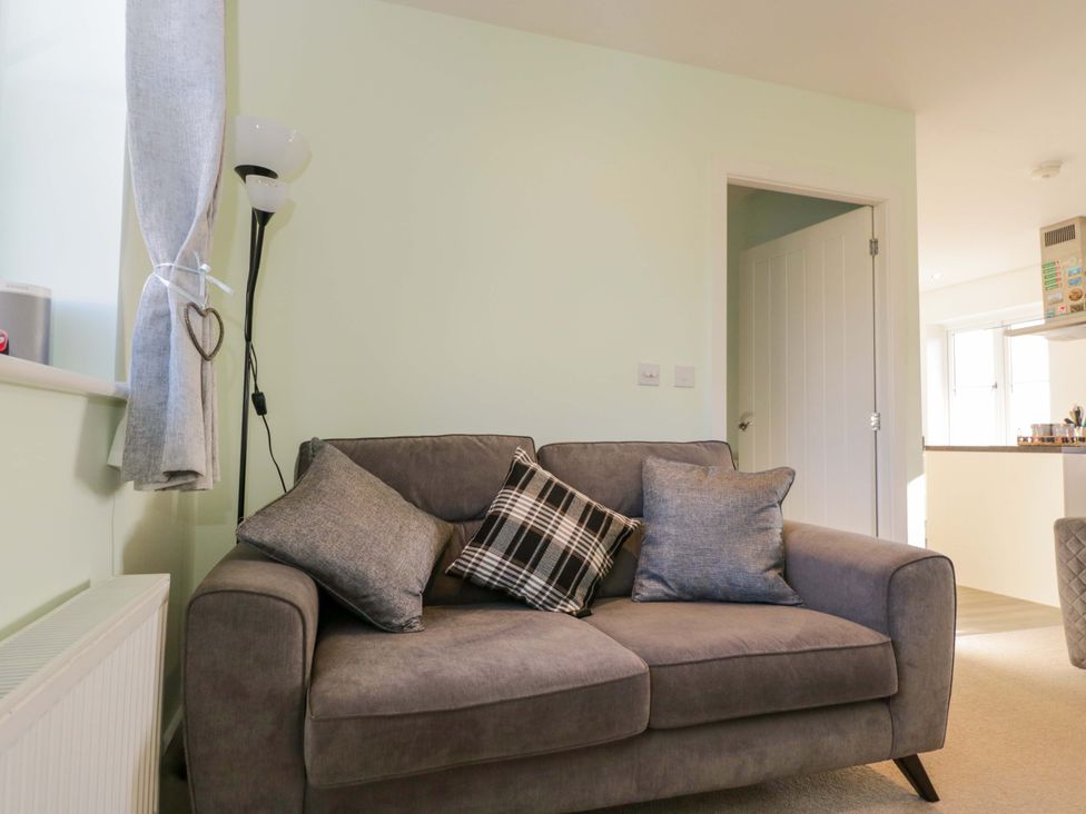 A living room with a sofa and cushions at Swallows Nest in Bourton-On-The-Water