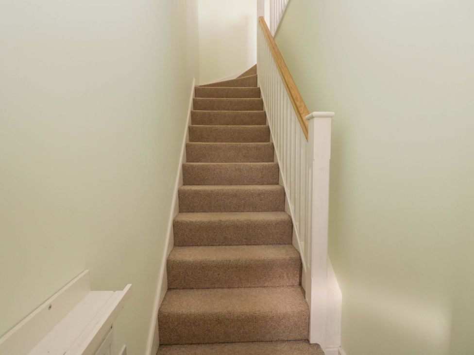 A staircase with carpet and a handrail at Swallows Nest in Bourton-On-The-Water