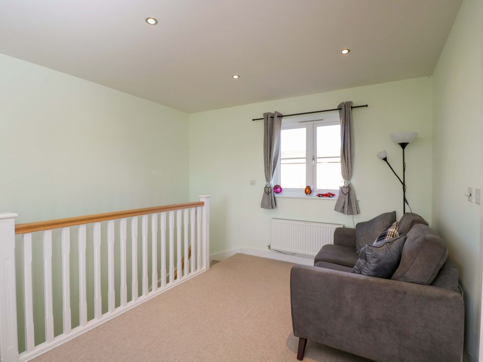 A landing with a sofa and a window at Swallows Nest in Bourton-On-The-Water