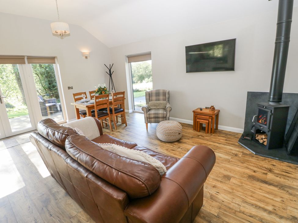 A living room with a sofa a dining table and a fireplace at Cadno in Llanybydder