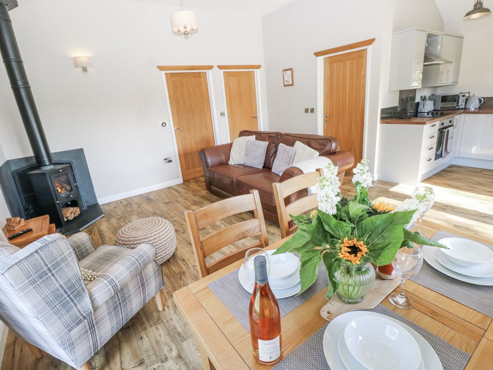A living room with a sofa a dining table and kitchen appliances at Cadno in Llanybydder