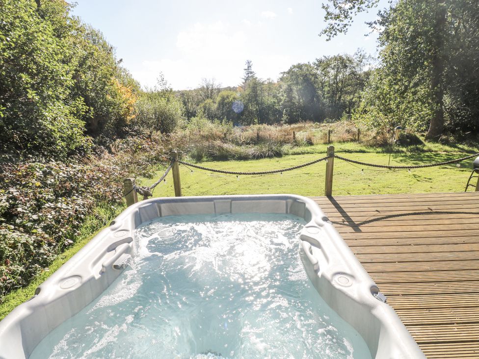 A hot tub overlooking a garden at Cadno in Llanybydder