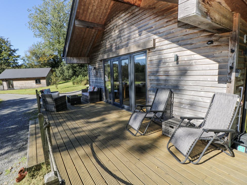 A patio with chairs and a table outside a wooden building at Cadno in Llanybydder