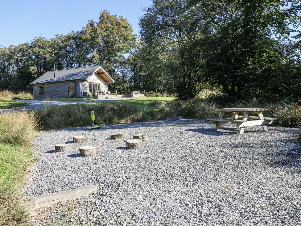 An outdoor area with a picnic table and logs at Cadno Llanybydder