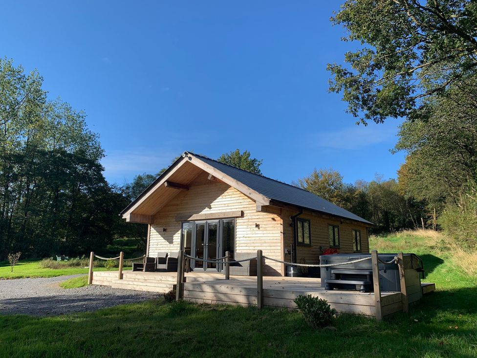 A cabin with a deck and hot tub at Cadno Aber near Llanybydder
