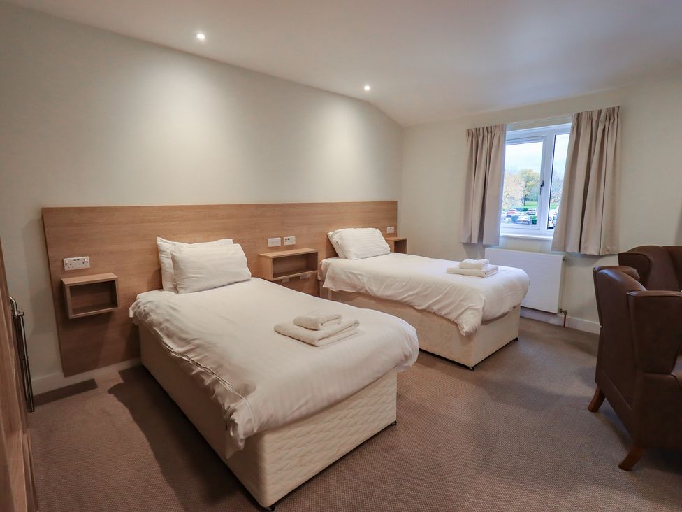 A bedroom with two single beds and a chair at Railway Retreat at Eamont Park Penrith