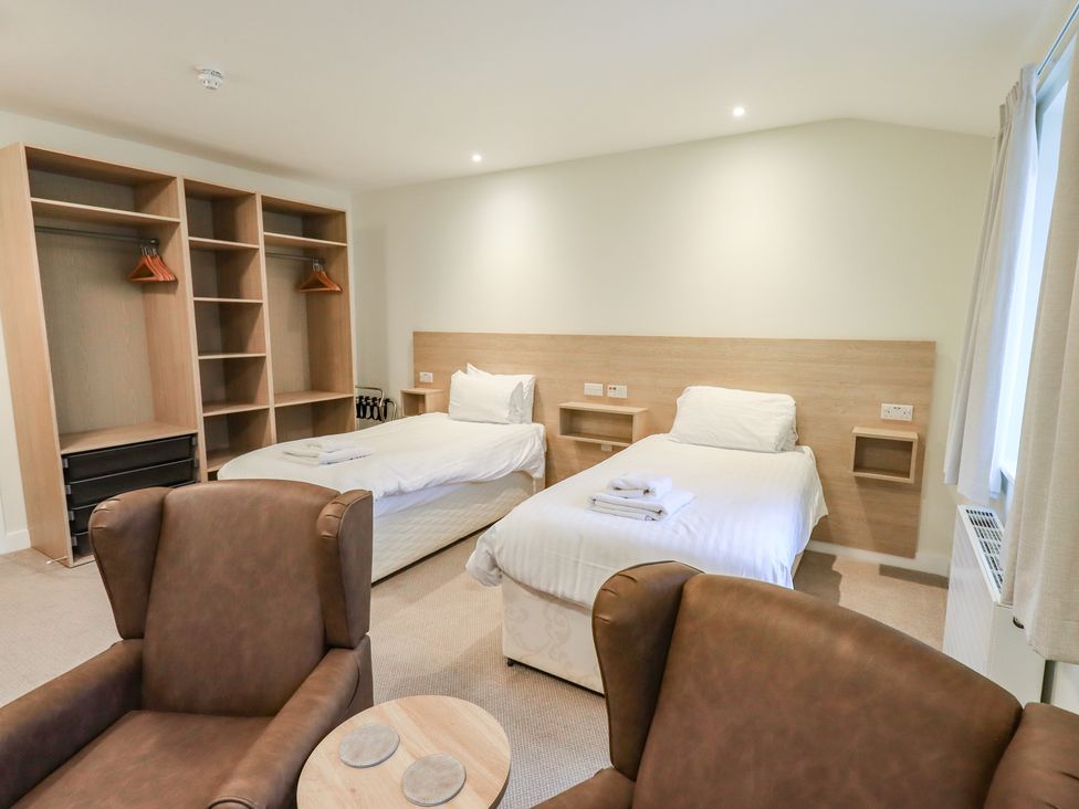 A bedroom with two beds and a wardrobe at Railway Retreat at Eamont Park, Penrith
