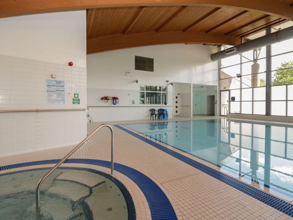 A swimming pool area with a jacuzzi and chairs at Railway Retreat at Eamont Park Penrith