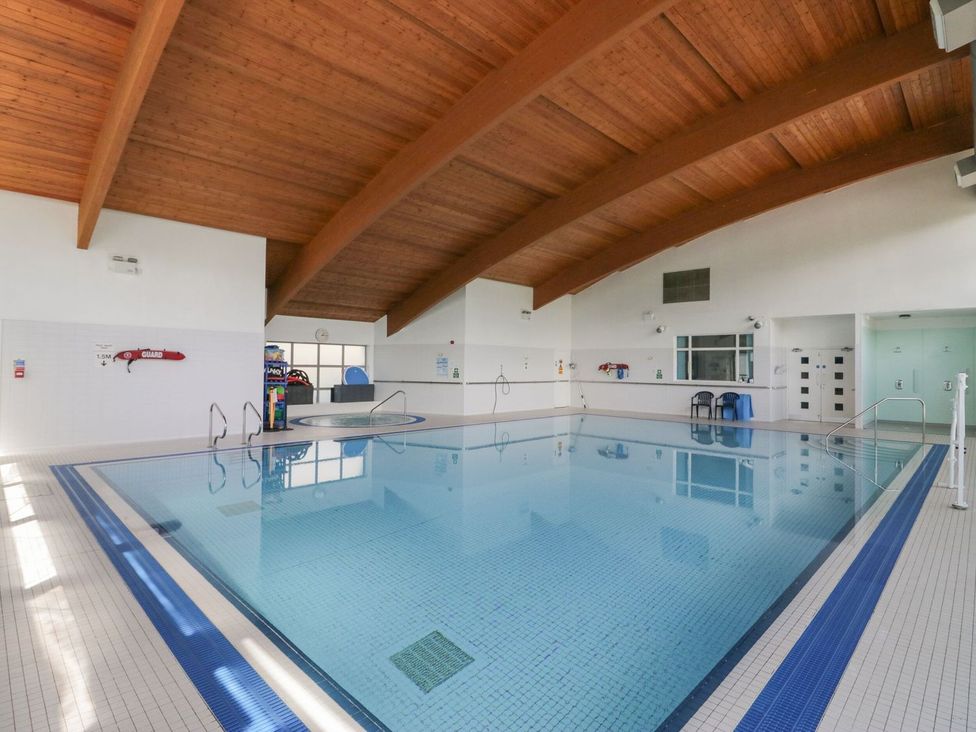 An indoor swimming pool with a ladder and chairs at Railway Retreat at Eamont Park Penrith