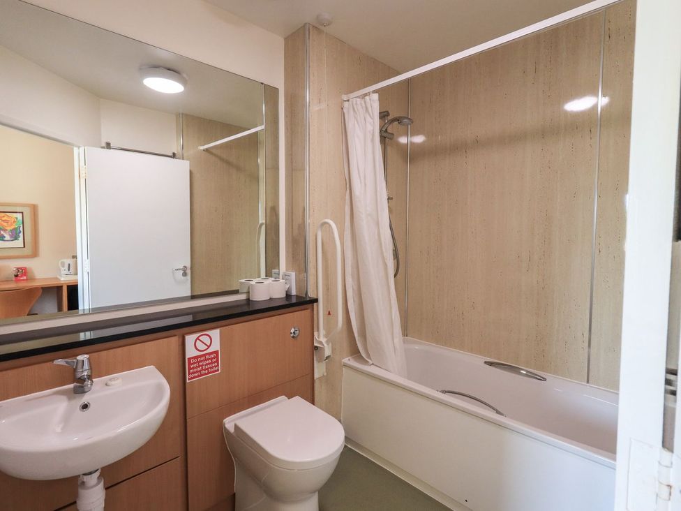 A bathroom with a sink, toilet, and shower over the tub at Thacka Beck Retreat at Eamont Park Penrith