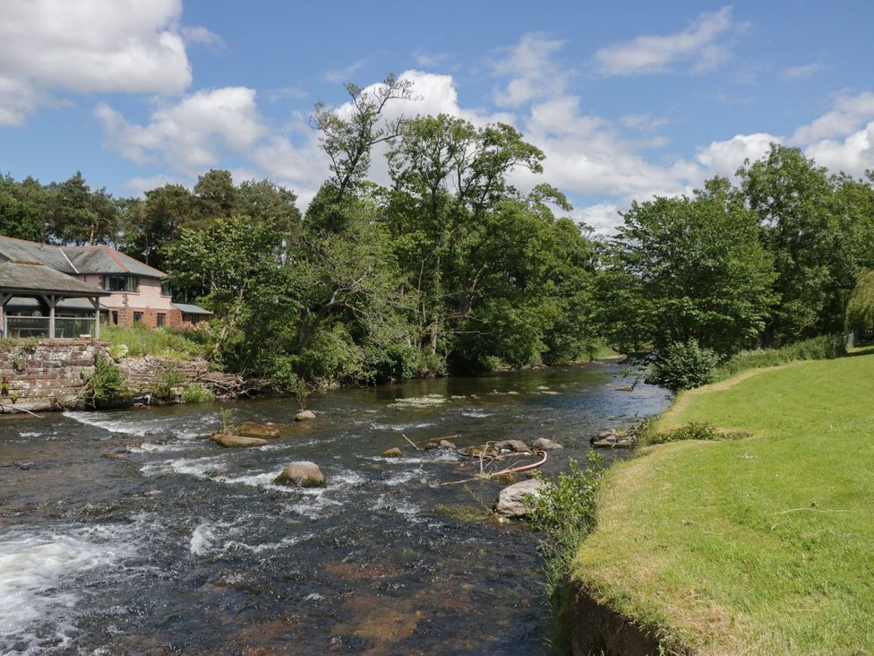 A river with trees and a house at Thacka Beck Retreat at Eamont Park Penrith