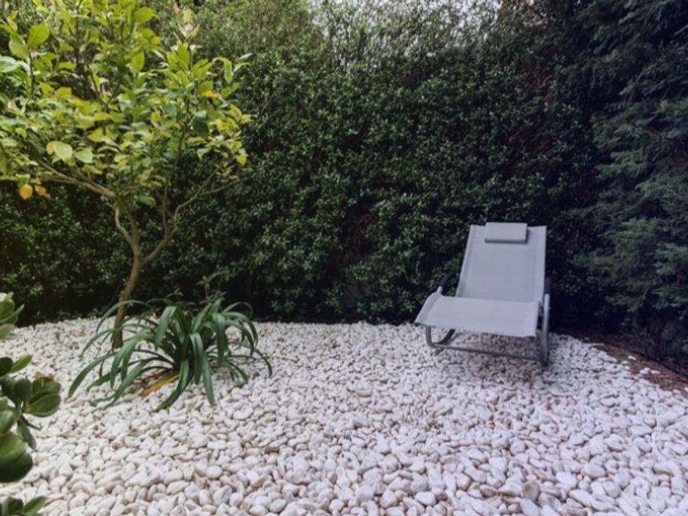 A garden with a lounge chair and pebbles at the property
