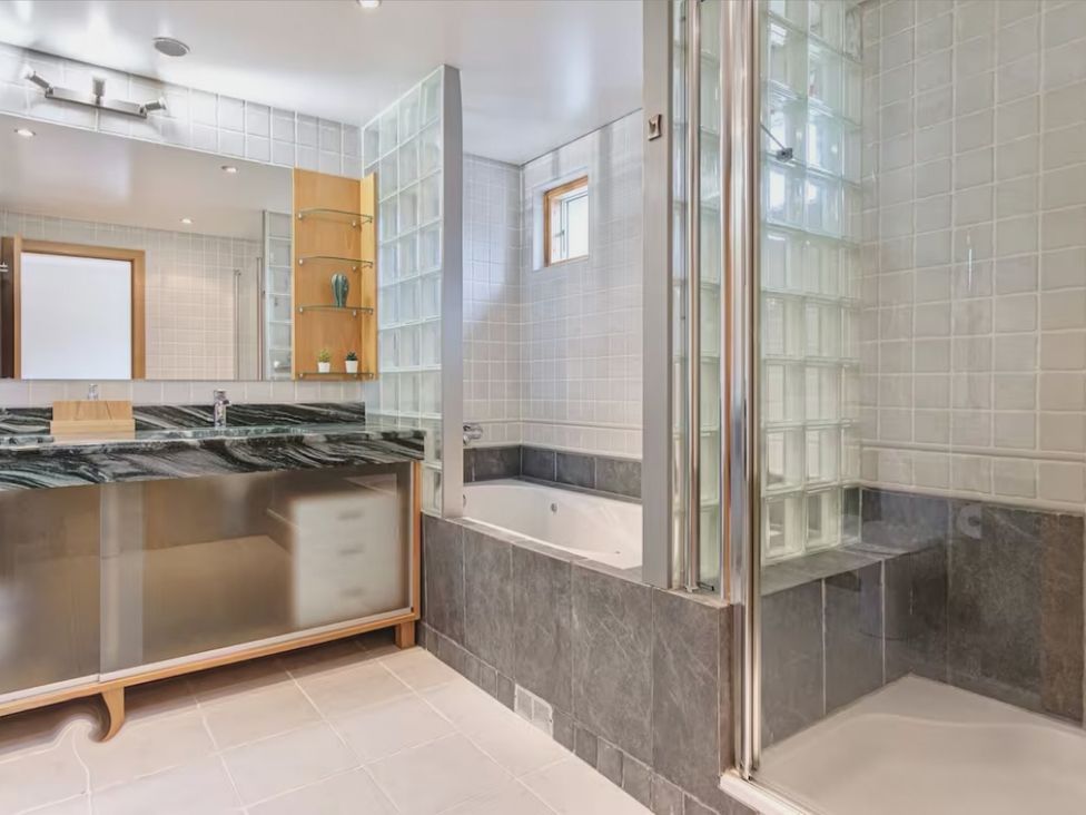 A bathroom with a sink, mirror, bathtub, and shower at The Old Barn in Manchester