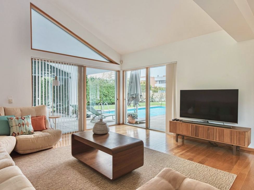 A living room with a television and sliding doors leading to a pool at a property