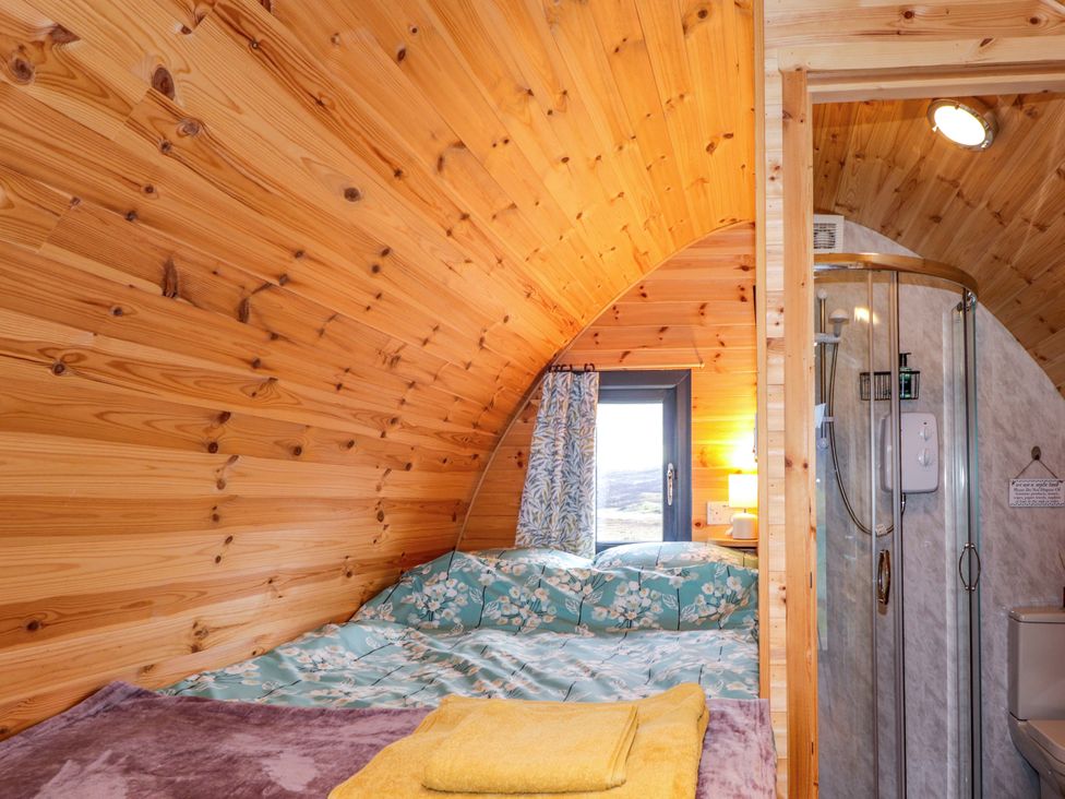 A bedroom with a bed and shower at The Pod at Greenbank Isle of Skye