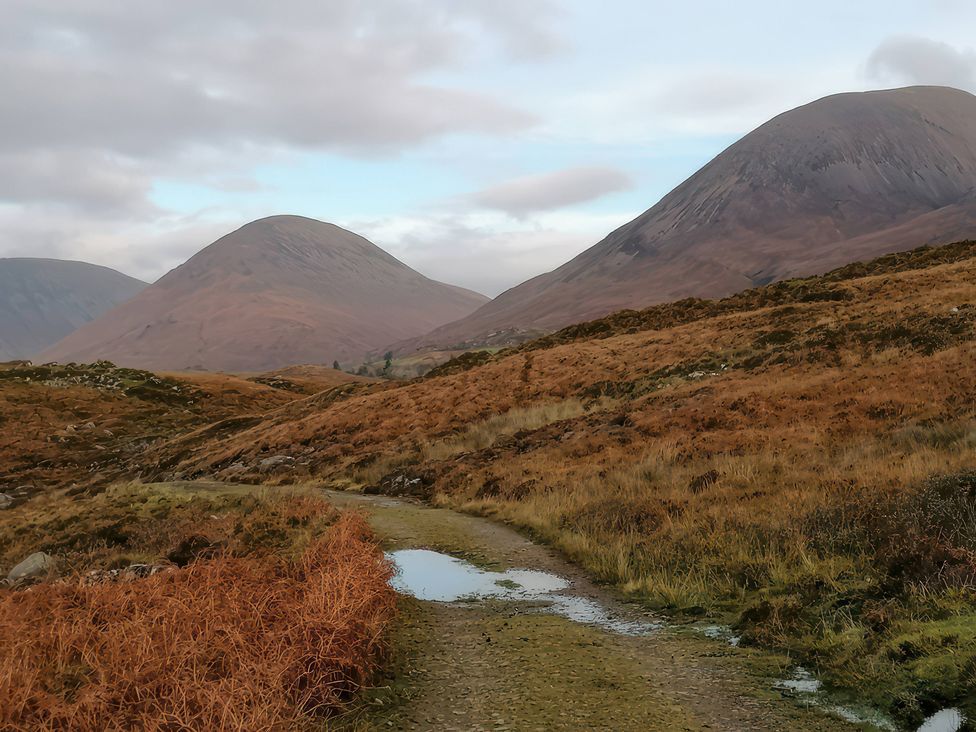 A path with puddles between mountains at The Pod at Greenbank Kilbride near Broadford
