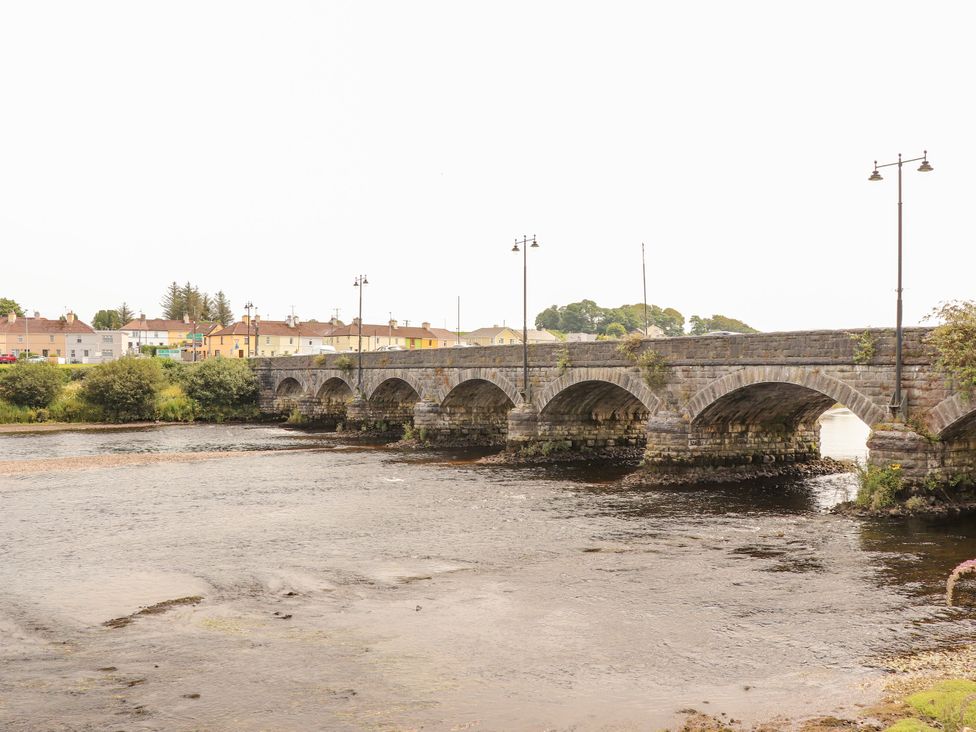 A stone bridge over a river with buildings and trees in the background at Shamrock House in Killorglin, County Kerry
