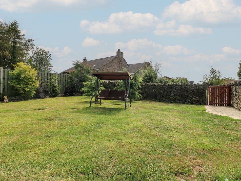 A garden with a swing seat and stone wall at Wigley House Farm Bungalow Chesterfield