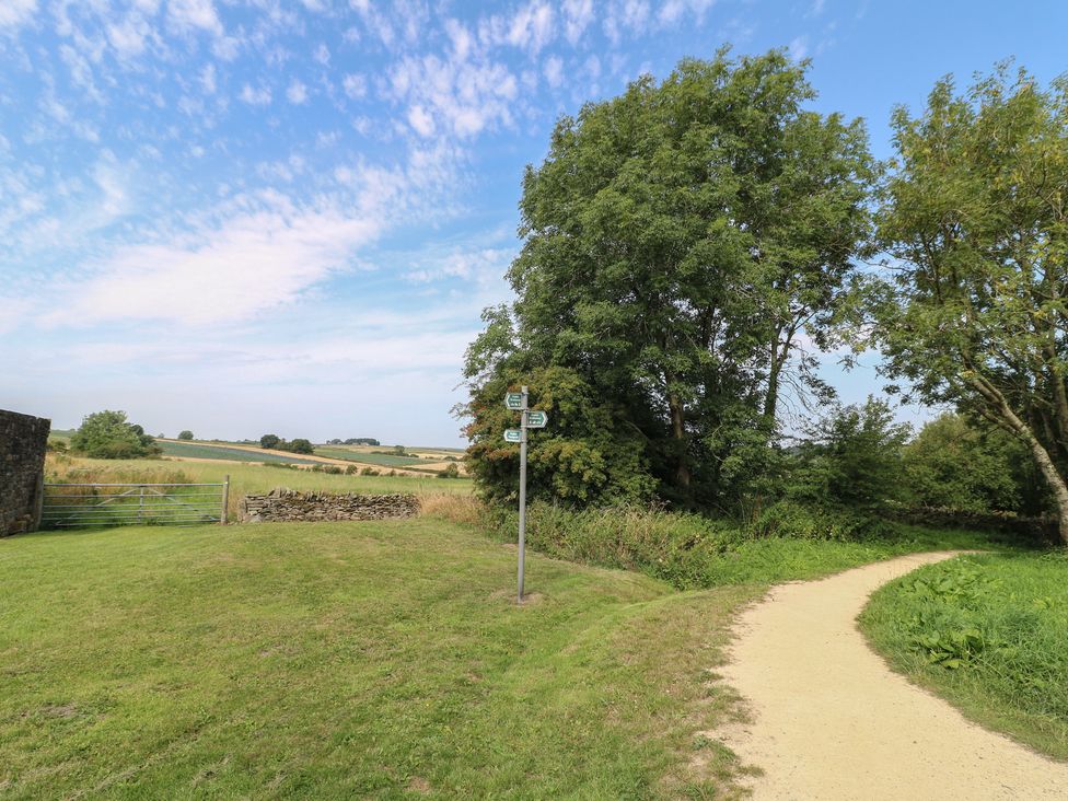 An outdoor scene with a path, trees, and a signpost at Wigley House Farm Bungalow Chesterfield