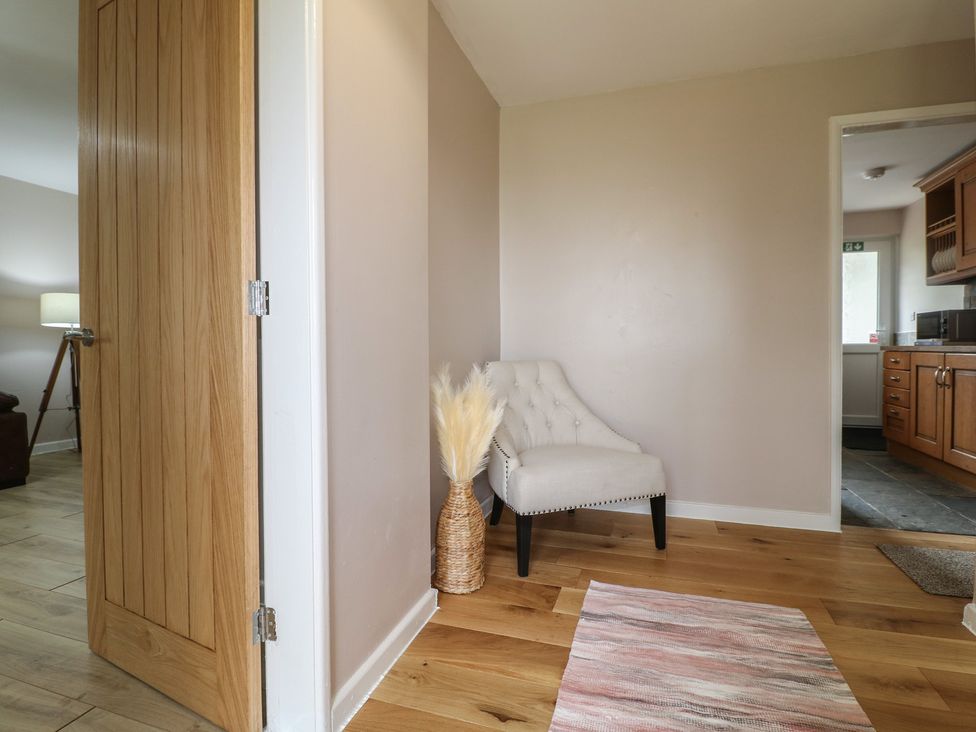 A hallway with a chair and flower arrangement at Wigley Farm House Cottage Chesterfield