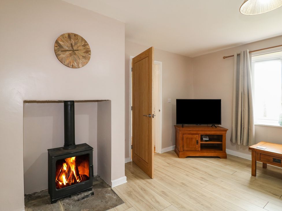 A living room with a wood burning stove and a television at Wigley Farm House Cottage Chesterfield