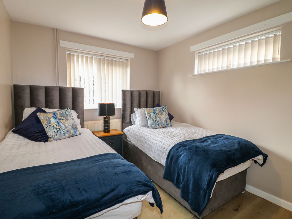 A bedroom with two beds and a bedside lamp at Wigley Farm House Cottage Chesterfield