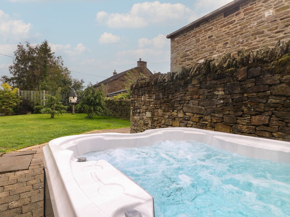 A hot tub and stone wall in a garden at Wigley Farm House Cottage Chesterfield