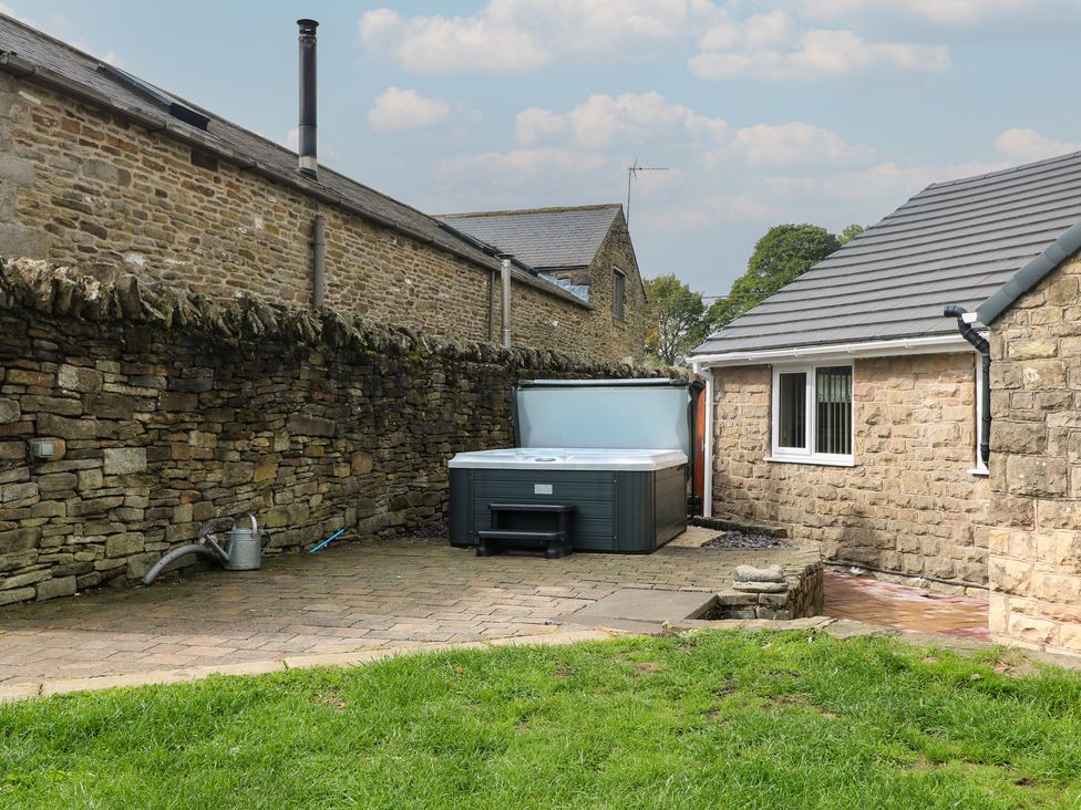 An outdoor area with a hot tub and stone walls at Wigley Farm House Cottage Chesterfield
