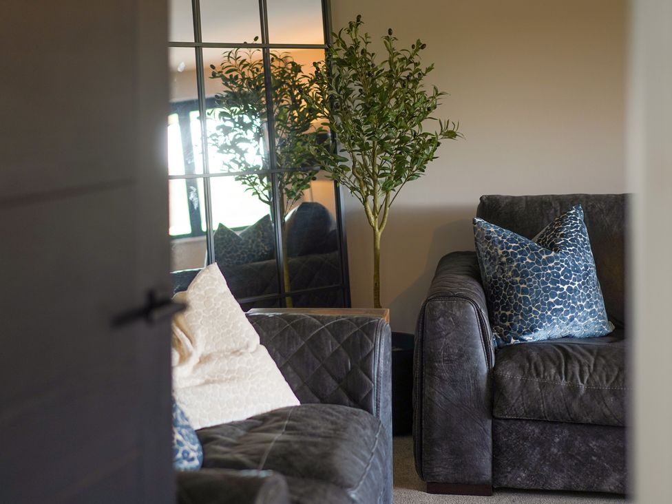 A living room with a sofa, cushion, plant, and mirror at Northstone House in Blackburn
