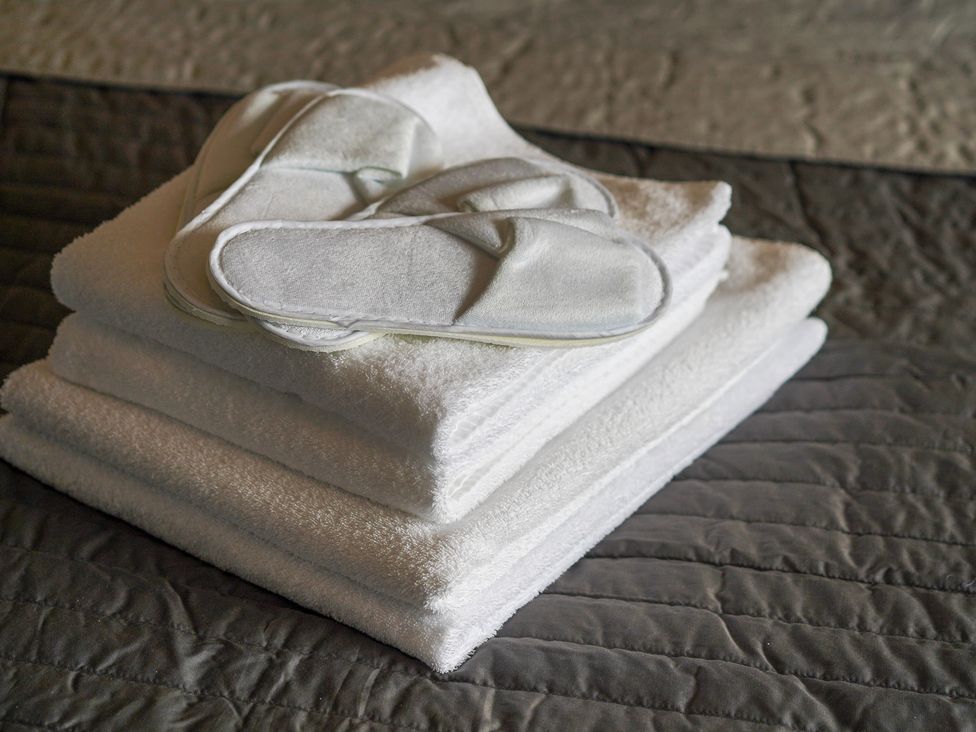 Towels and slippers stacked on a bed at Northstone House Blackburn