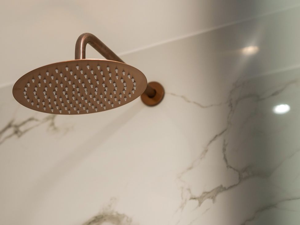 A shower head mounted on a marble wall at Northstone House Blackburn