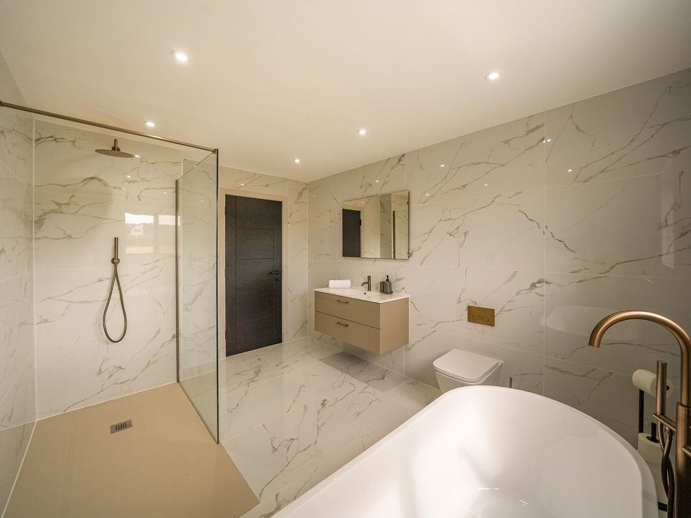 A bathroom with a bathtub, shower, and sink at Northstone House in Blackburn