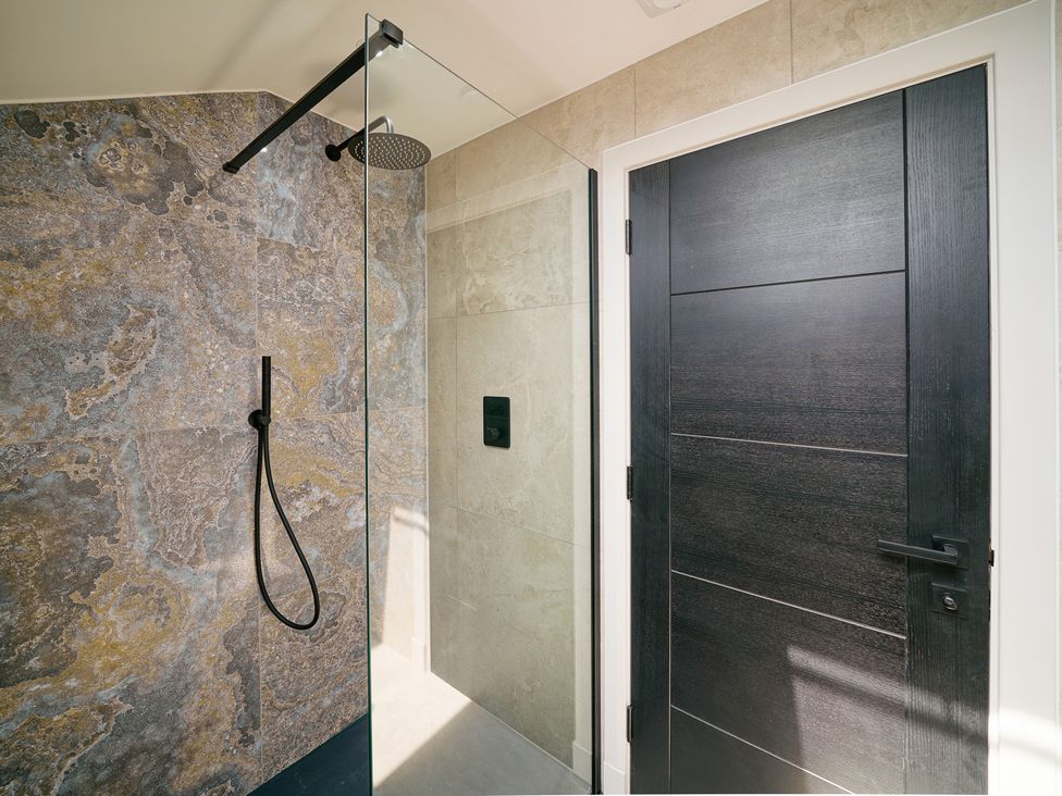 A shower area with a glass door and a black door at Northstone House Blackburn