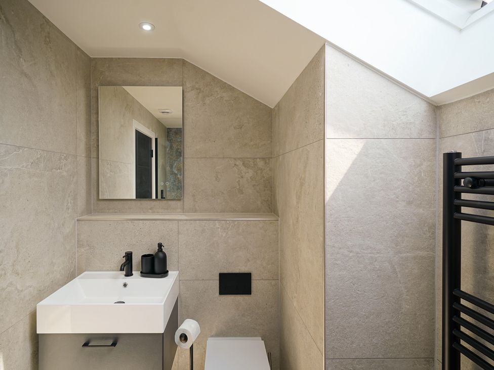 A bathroom with a sink, toilet, and mirror at Northstone House in Blackburn