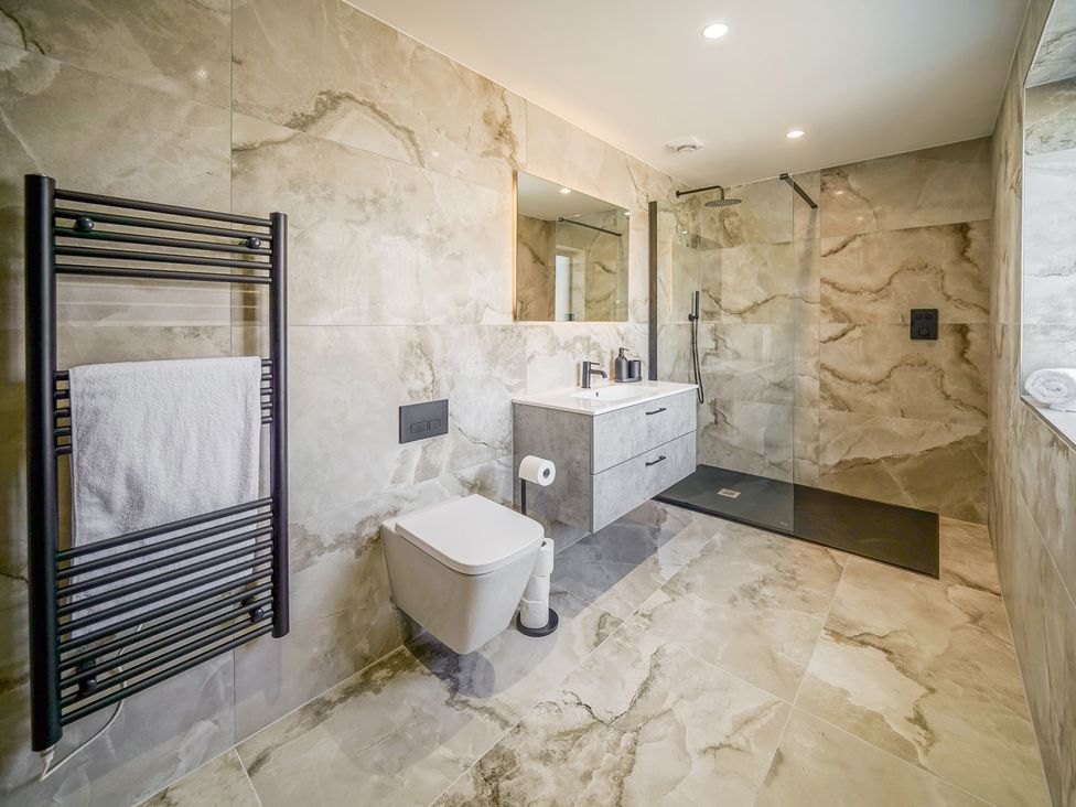 A bathroom with a shower, toilet, vanity unit and towel warmer at Northstone House Blackburn