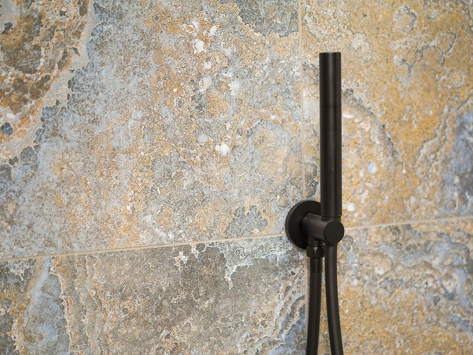 A showerhead attached to a wall in a bathroom at Northstone House Blackburn