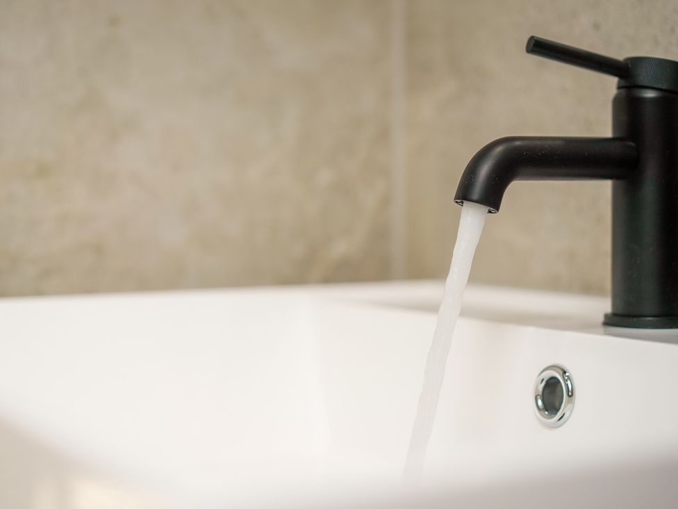 A sink with a black faucet and running water at Northstone House Blackburn