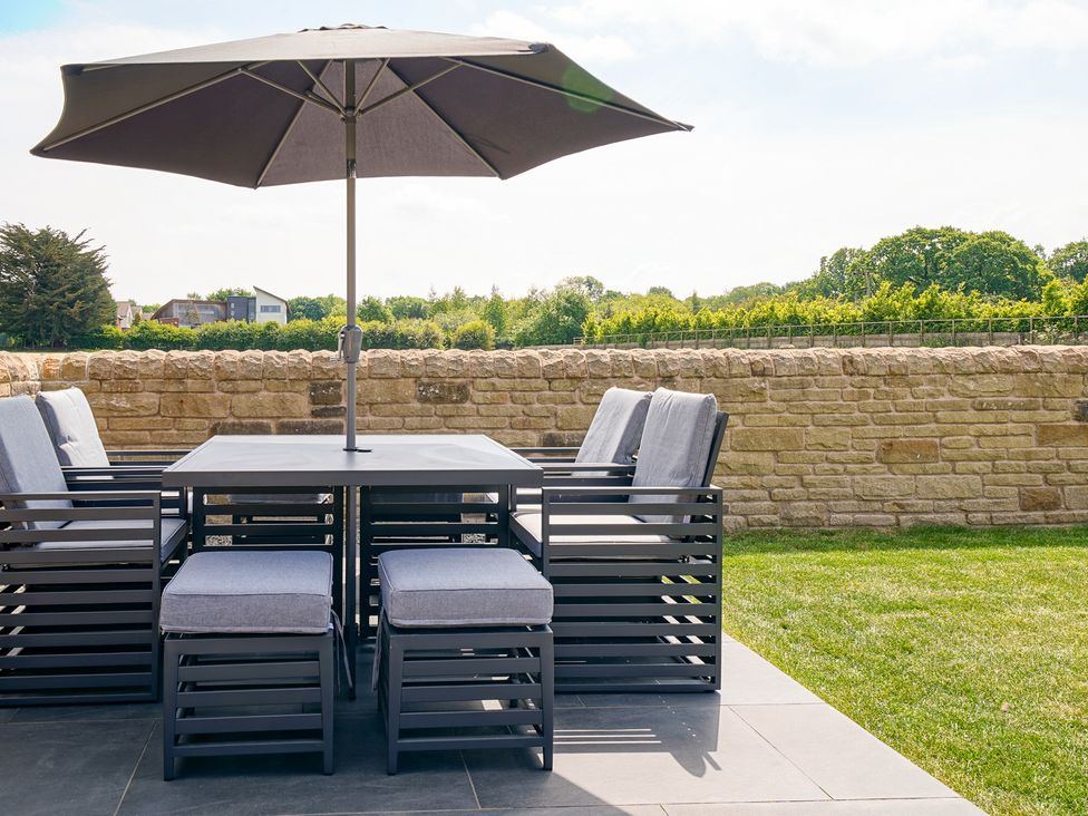 A patio set with chairs and an umbrella at Northstone House in Blackburn