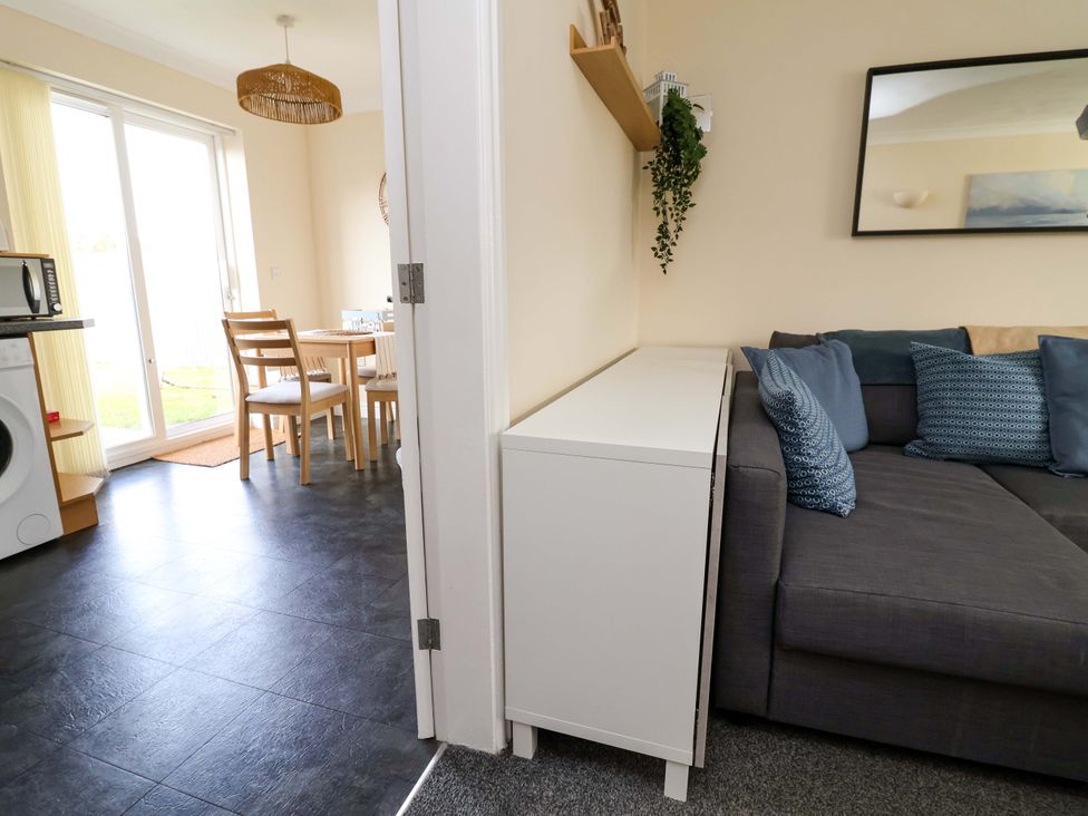 A living room with a sofa and dining table at The Beach Escape in Prestatyn