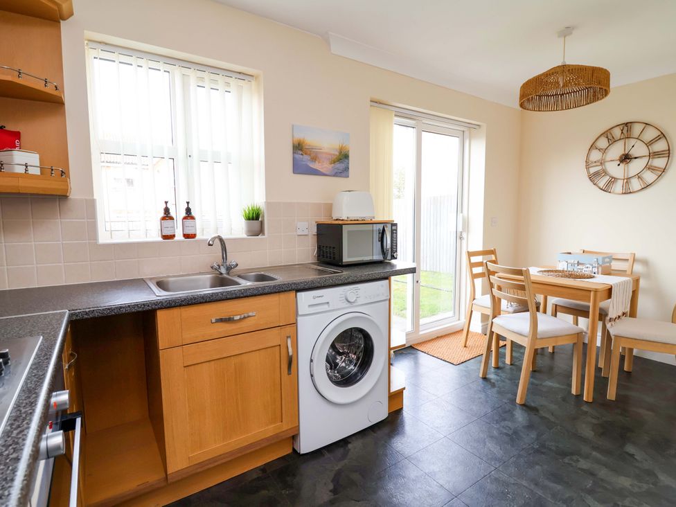 A kitchen with a washing machine and dining table at The Beach Escape in Prestatyn
