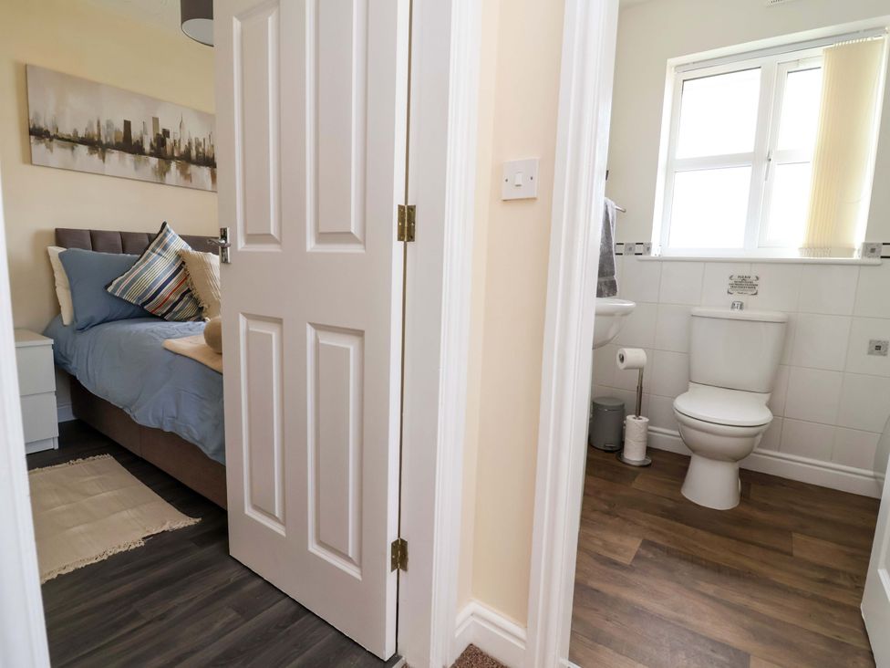 A bedroom with a bed and an adjacent bathroom at The Beach Escape in Prestatyn